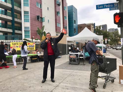 Pastor Tim Park beckons residents of Skid Row over to his tent ministry.