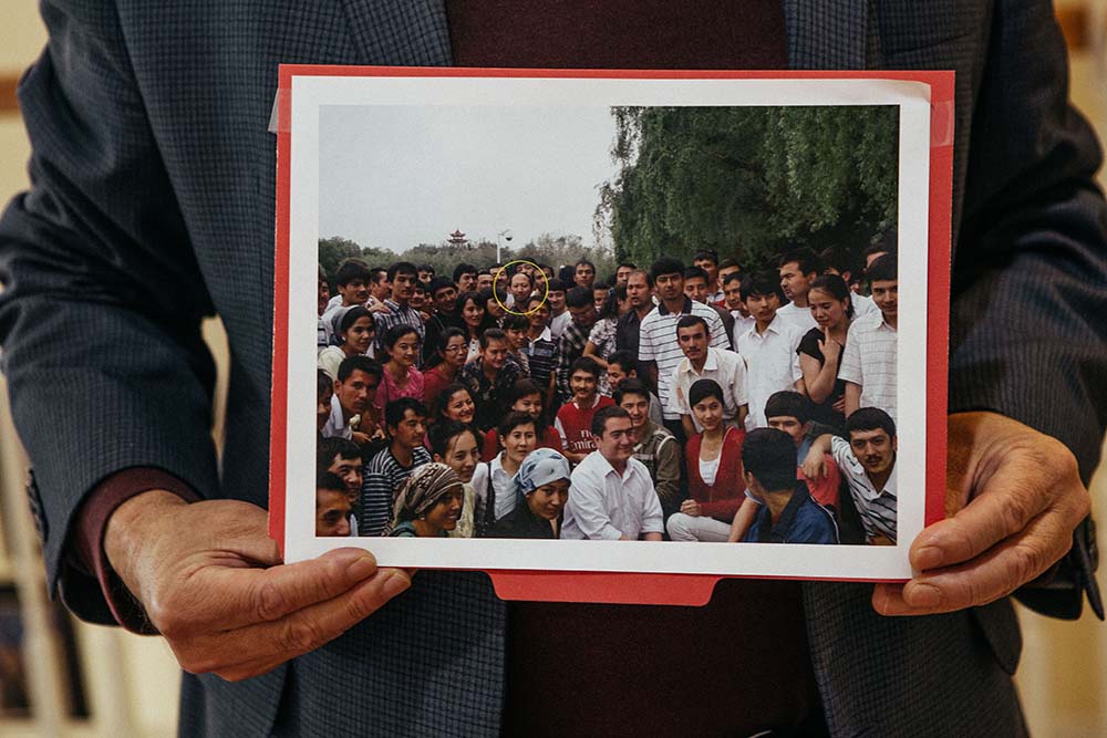 Erkin Sidick holds a photo of himself posing with dozens of students who he spoke with at Xinjiang University on his last visit in June 2009.