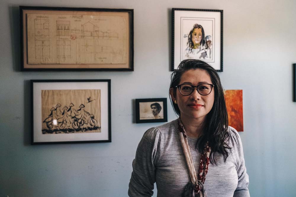 Human rights lawyer Kim Luu-Ng in front of a wall in her Alhambra home displaying art and blueprints from her childhood home to honor her family’s roots in Vietnam.