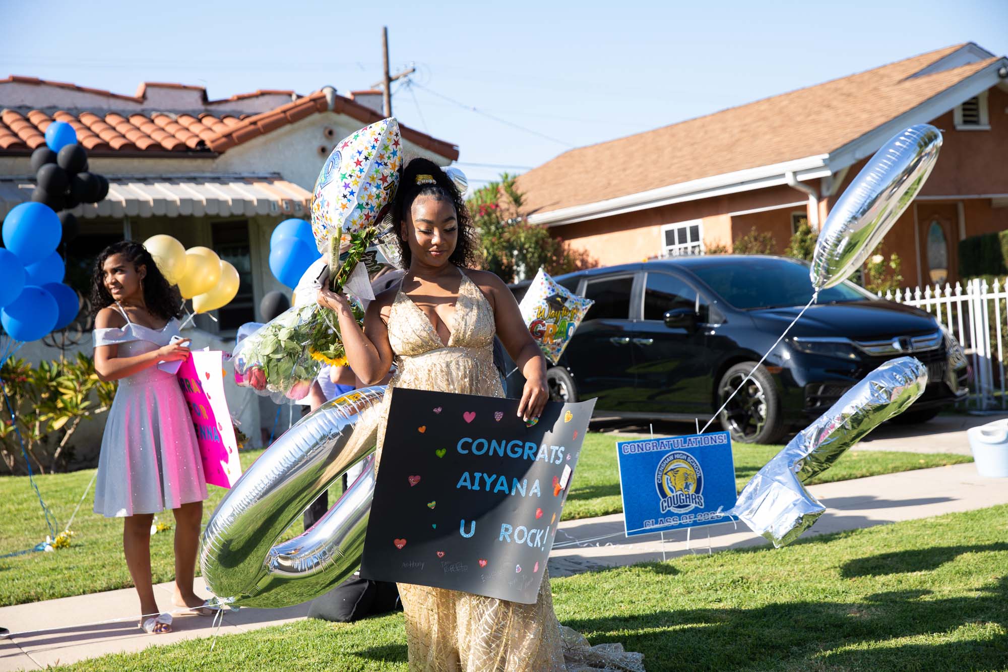 Carloads of family and friends wave, whistle and shower Aiyana Lopez-Spears with love, gifts and balloons in a drive-by party to celebrate her graduation from Crenshaw High School.