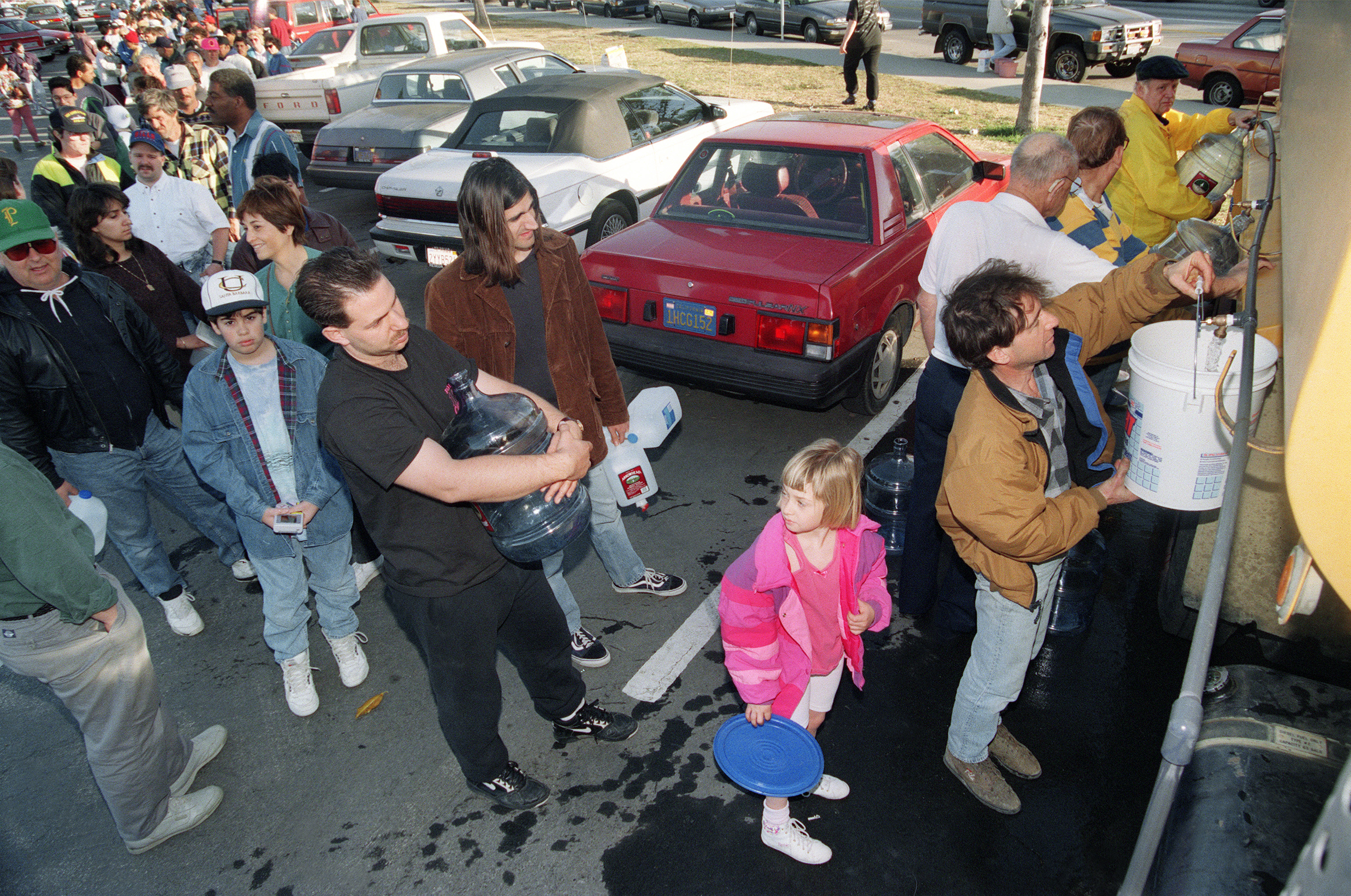 A resident fills a water jug on Jan. 18, 1994, at one of many water lines set up in the area to assist victims of the Northridge earthquake. Local authorities warned residents not to drink tap water after the quake broke many water mains in the area.